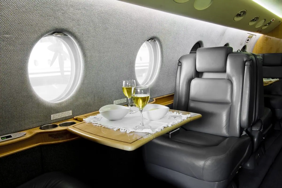 Sessel in der Kabine eines Gulfstream G150 neben einem gedeckten Tisch mit Gläsern