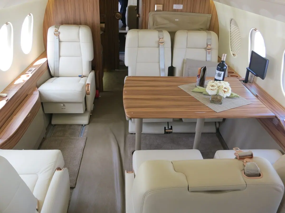 Konferenztisch für vier Personen im Falcon 2000LX, dahinter ein Clubsessel und ein Monitor