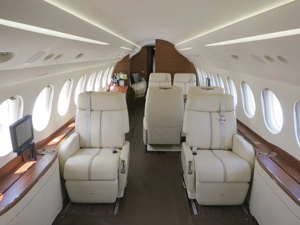 Vordere Kabine eines Falcon 7X: vier cremefarbene Clubsessel aus Leder, je zwei einander gegenüber, mit Seitenablagen aus Walnussholz