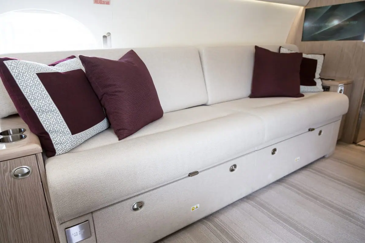 Cremefarbenes Sofa mit Kissen an der Kabinenwand eines Gulfstream G550